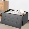 A storage ottoman filled with stuffed animals and blankets, with a wooden dresser in the background. Anteprima dell’immagine prodotto