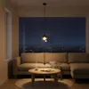 A living room scene at night with a couch, coffee table, and a large window overlooking a city skyline. Produktbild-Vorschau