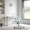 A modern office chair is placed in a minimalist office setting with a desk, shelves, and a large window. Produktbild-Vorschau