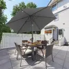 A patio set with a large umbrella is set up on a paved patio area next to a house. Produktbild-Vorschau