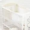 A white crib with bedding and a teddy bear motif. Voir les images du produit