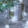 A string of white LED lights with spherical bulbs is draped around a gift-wrapped box and a vase of flowers. Anteprima dell’immagine prodotto