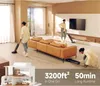 Three people are cleaning a modern living room with vacuum cleaners. A large orange sofa is in the center of the room. A television is mounted on the wall. Produktbild-Vorschau