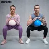 A man and a woman are performing squats while holding kettlebells. Produktbild-Vorschau