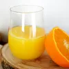 A clear glass of orange juice sits on a wooden slice next to a half orange. Produktbild-Vorschau