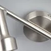 A close-up view of a brushed nickel track light fixture mounted on a light gray wall. Produktbild-Vorschau