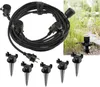 A black extension cord with multiple outlets and stakes for outdoor use, shown against a natural outdoor background. Produktbild-Vorschau