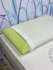 A pillow with a green perforated insert is placed on a mattress. Produktbild-Vorschau