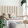 A modern living room with a cream-colored sofa and a knitted pouf. Anteprima dell’immagine prodotto