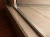 A close-up view of a shower door track and marble-like surface. Produktbild-Vorschau