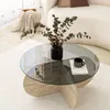 A modern living room setting with a round glass coffee table. Produktbild-Vorschau