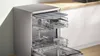 A dishwasher with its racks pulled out, set in a kitchen environment. Voir les images du produit