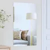 A mirror reflecting a living room scene with a sofa and a floor lamp. Produktbild-Vorschau