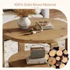A round coffee table with two tiers, decorated with a vase of dried flowers and wooden beads. A small vintage-style radio sits on the lower tier. A circular inset shows a pile of cut logs. Produktbild-Vorschau