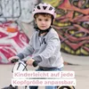 A young boy wearing a pink helmet rides a balance bike in front of a graffiti-covered wall. Anteprima dell’immagine prodotto