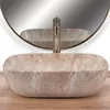 A beige oval countertop sink with a brass faucet in front of a round mirror. Anteprima dell’immagine prodotto