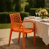 An orange chair is placed on a patio next to a table set for a meal. Anteprima dell’immagine prodotto