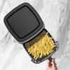 An overhead view of an open air fryer filled with french fries, with a hand holding the basket. Produktbild-Vorschau
