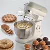 A vintage-style kitchen mixer with a bowl of batter, surrounded by baked goods like a tart, bread, muffins, and a ring cake. Náhled obrázku produktu