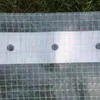 A close-up view of a green grid plastic sheeting with a white strip containing three circular holes. Produktbild-Vorschau