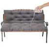 A hand is pouring water onto a dark gray bench cushion to demonstrate its water-repellent properties. Produktbild-Vorschau