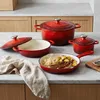A set of red cast iron cookware is displayed on a marble countertop. Anteprima dell’immagine prodotto