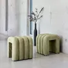 Two green upholstered stools are placed in a modern interior with concrete walls and a window. Produktbild-Vorschau