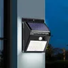 A solar-powered wall light with LED lights and a PIR sensor is mounted on a wall next to a window. Produktbild-Vorschau