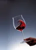 A hand holding a glass of red wine, with the wine swirling inside. Podgląd zdjęcia produktu