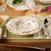 A table setting with plates, cutlery, and a glass of wine. Náhled obrázku produktu