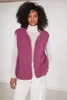 A woman wearing a pink vest over a white turtleneck and white pants. Produktbild-Vorschau
