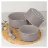 A set of taupe-colored pots with a gray handle accessory, arranged on a woven mat. Podgląd zdjęcia produktu