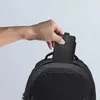 A hand is placing a black phone case into a black backpack. Produktbild-Vorschau