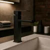A black faucet is shown in a modern bathroom setting. Náhľad obrázku produktu