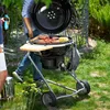 People are grilling food on a charcoal grill in a garden. Produktbild-Vorschau