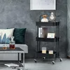 A black three-tiered rolling cart is shown in a living room setting next to a sofa and coffee table. Anteprima dell’immagine prodotto