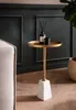 A small round side table with a gold top and a marble base, placed next to a sofa in a room with dark green paneled walls and a wooden floor. Podgląd zdjęcia produktu