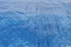 A close-up, angled view of a blue tarp with a woven grid pattern. Produktbild-Vorschau