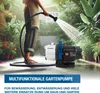 A person is watering plants in a garden with a water pump in the background. Produktbild-Vorschau