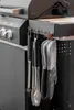 Close-up view of grilling tools and oven mitts hanging from a grill. Produktbild-Vorschau