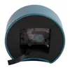 The back of a dark blue alarm clock is shown, revealing the internal clockwork mechanism. Produktbild-Vorschau