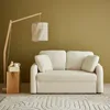 A cream-colored sofa with a wooden floor lamp and a small wooden side table. Anteprima dell’immagine prodotto