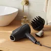 A black Panasonic hairdryer with attachments sits on a wooden countertop next to a sink and a bottle of perfume. Anteprima dell’immagine prodotto
