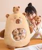 A woman is holding a small plush toy next to a large plush toy that has smaller plush toys inside it. Anteprima dell’immagine prodotto