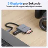 A VOOMY USB-C card reader with an SD card inserted, connected to a laptop, with a camera lens in the background. Produktbild-Vorschau