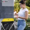 A woman is shown discarding items into a yellow trash can stand. Anteprima dell’immagine prodotto