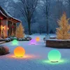 A snowy garden scene at dusk, decorated for the holidays with illuminated spherical garden lights. Produktbild-Vorschau