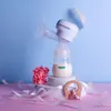 A breast pump with a bottle of milk, a flower, and a wooden toy elephant on a pink and blue background. Podgląd zdjęcia produktu