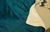 A close-up view of a teal blanket with a cream sherpa lining draped over a sofa. Produktbild-Vorschau