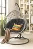 A hanging egg chair with a cushion and blanket in a room with a bookshelf. Produktbild-Vorschau